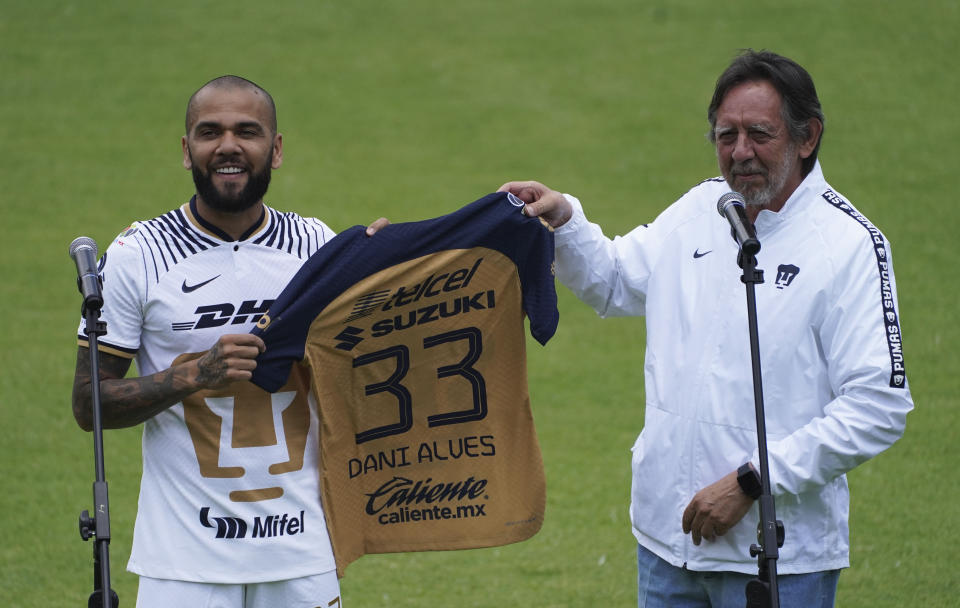 Brazilian Dani Alves receives his official Pumas' jersey from club president Leopoldo Silva, during his presentation as a new member of the Pumas UNAM soccer club, on the pitch at the Pumas training facility in Mexico City, Saturday, July 23, 2022. (AP Photo/Marco Ugarte)