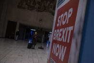 Passengers walk near a banner from the anti-Brexit campaign in Brussels, Sunday, Dec. 20, 2020. The EU and the United Kingdom were still working Sunday on a "last attempt" to clinch a post-Brexit trade deal, with EU fishing rights in British waters the most notable remaining obstacle to avoid a chaotic and costly changeover on New Year. (AP Photo/Virginia Mayo)