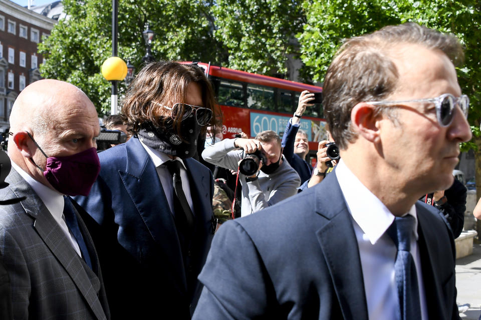 Johnny Depp, second left, wearing a protective mask arrives at the Royal Court of Justice, in London, Tuesday, July 7, 2020. Johnny Depp is suing a tabloid newspaper for libel over an article that branded him a "wife beater." On Tuesday, a judge at the High Court is due to begin hearing Depp's claim against The Sun's publisher, News Group Newspapers, and its executive editor, Dan Wootton, over the 2018 story alleging he was violent and abusive to then-wife Amber Heard. Depp strongly denies the claim. (AP Photo/Alberto Pezzali)