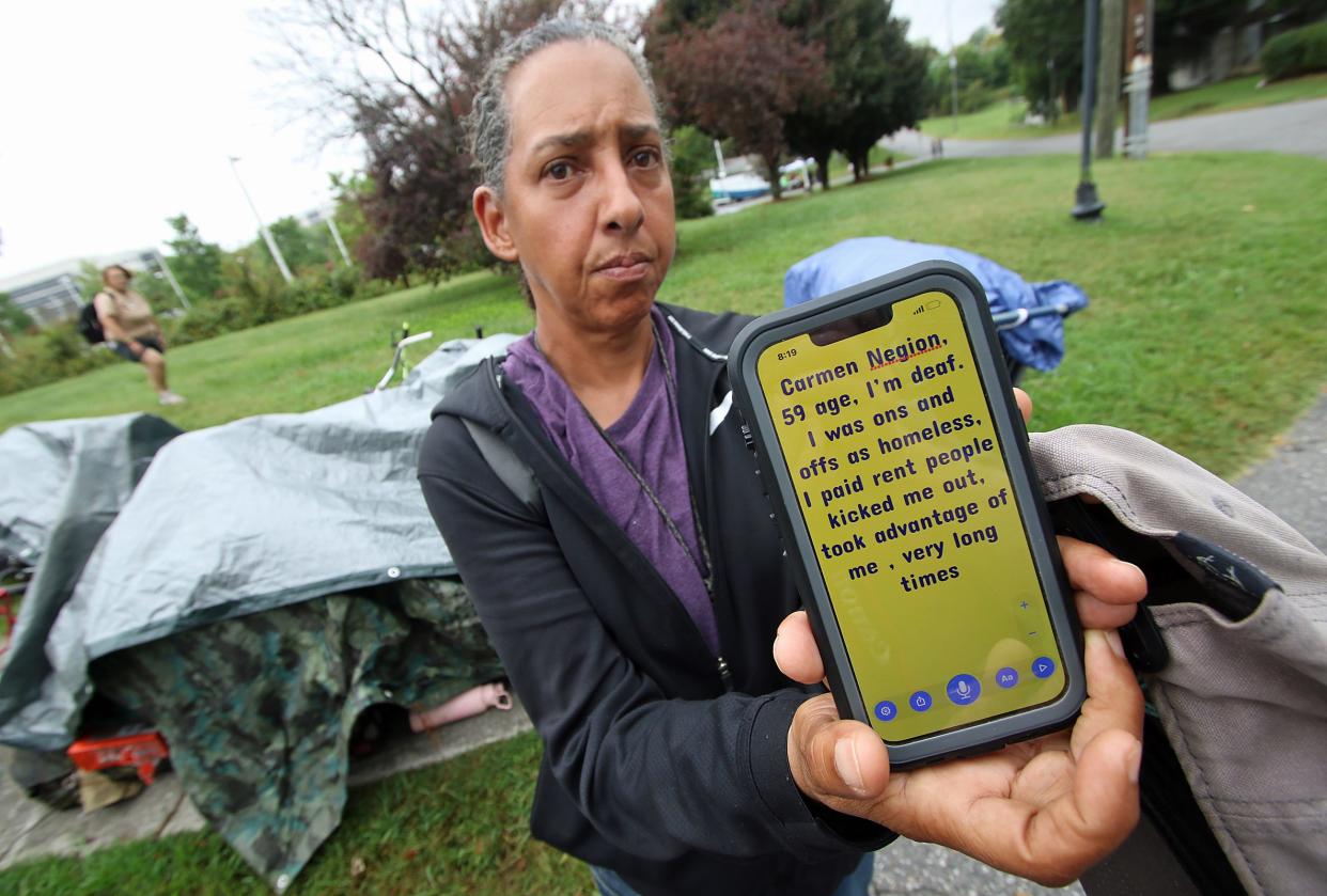 Carmen Negion communicates through her cell phone as she and others vacate the homeless encampment behind Faith, Hope and Love Community Enrichment Ministries on North Oakland Street early Monday morning.