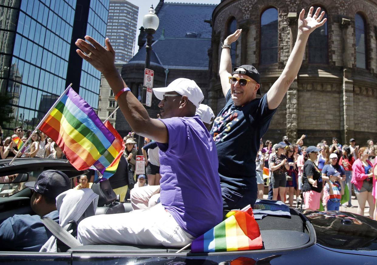 Boston Pride 2019 Grand Marshal Dale Mitchell, right, waves as he rides in a convertible during the LGBTQ Pride Parade, Saturday, June 8, 2019, in Boston.