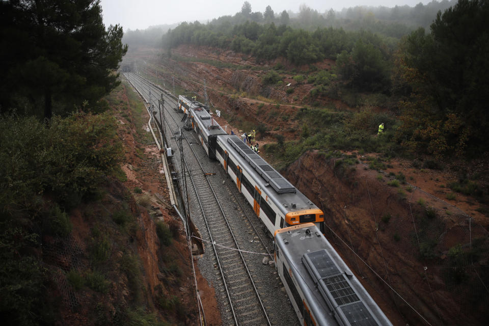 Firefighters and emergency workers stand by the derailed cars of a commuter train that went off the tracks near Barcelona, Spain, Tuesday, Nov. 20, 2018. Authorities in Spain say one person has died and six have been slightly injured when a landslide derailed the commuter train traveling toward Barcelona early on Tuesday. (AP Photo/Emilio Morenatti)