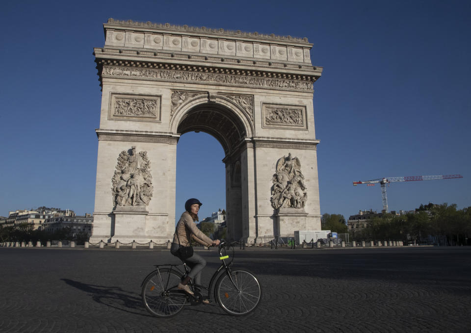 Una mujer pasa con su bicicleta frente a la Place Charles de Gaulle de París el 14 de abril del 2020. La pandemia de coronavirus está dando nuevo impulso a las bicicletas como alternativa al trasporte público. (AP Photo/Michel Euler, File)