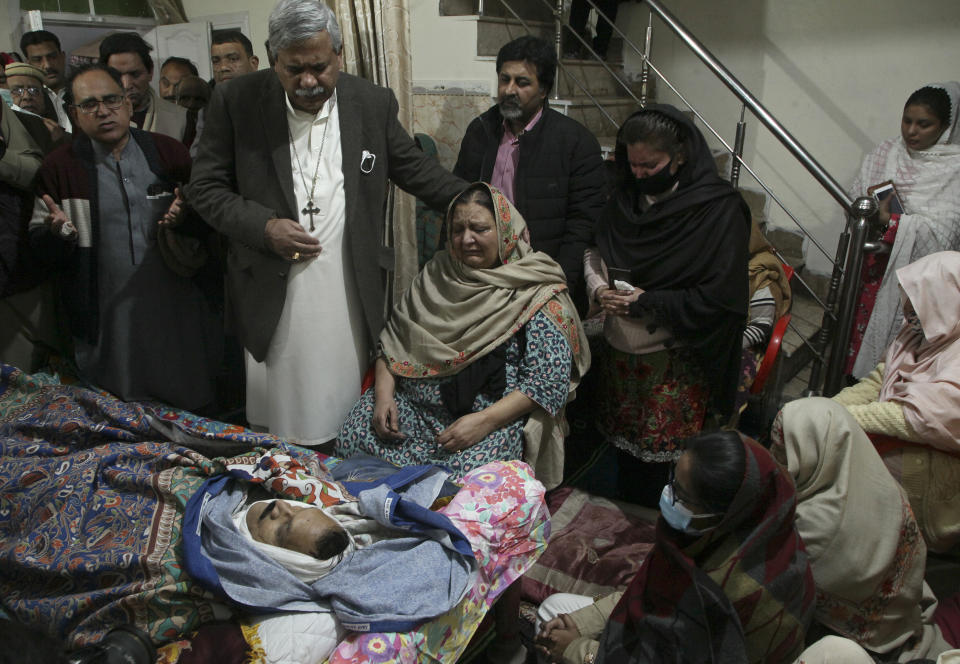 Relatives of Christian priest Father William Siraj, 75, who was killed by unknown gunmen, mourn next to his body at his home in Peshawar, Pakistan, Sunday, Jan. 30, 2022. Police said gunmen killed Siraj and wounded another priest as they were driving home from Sunday Mass in Pakistan’s northwestern city of Peshawar. (AP Photo/Muhammad Sajjad)