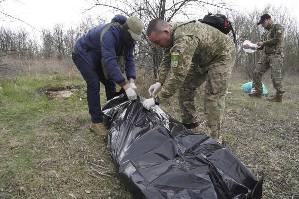 Ukrainian servicemen pack the dead body of a Russian soldier, killed in a recent battle in the Kharkiv region, Ukraine, Saturday, April 8, 2023. (AP Photo/Andrii Marienko)