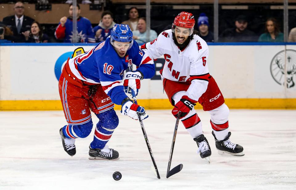 Jan 2, 2024; New York, New York, USA; New York Rangers left wing Artemi Panarin (10) and Carolina Hurricanes defenseman Jalen Chatfield (5) battle for the puck during the first period at Madison Square Garden.