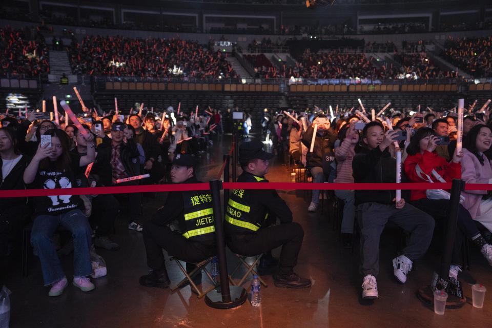 Security guards watch over fans of Chinese rappers during a performance in Chengdu in southwestern China's Sichuan province, Saturday, March 16, 2024. China's rap industry is flourishing, after a pause in 2018 that left many wondering if it'd be banned by the country's powerful censors. By staying clear of the government's red lines, the genre's explosive growth is able to continue. (AP Photo/Ng Han Guan)