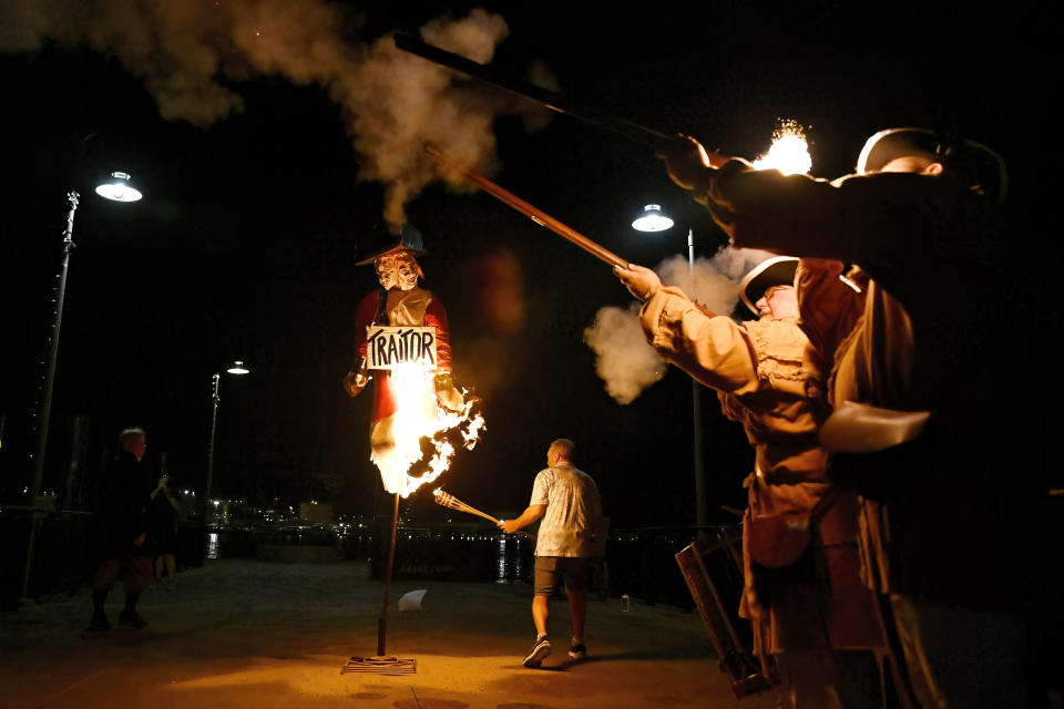 New London Mayor Michael E. Passero lights an effigy of Benedict Arnold as guns fire during the annual Burning of Benedict Arnold Festival, Saturday, Sept. 9, 2023, in New London, Conn. The burning of Arnold marks the anniversary of the day in September 1781 that the Connecticut native led British troops into the city and burned most of it to the ground. (AP Photo/Jessica Hill)