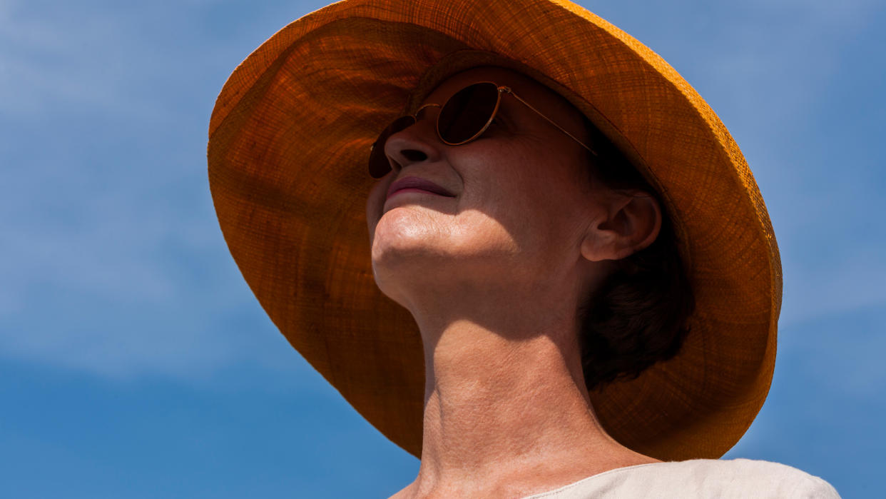  Smiling woman wearing summer hat and sunglasses. 