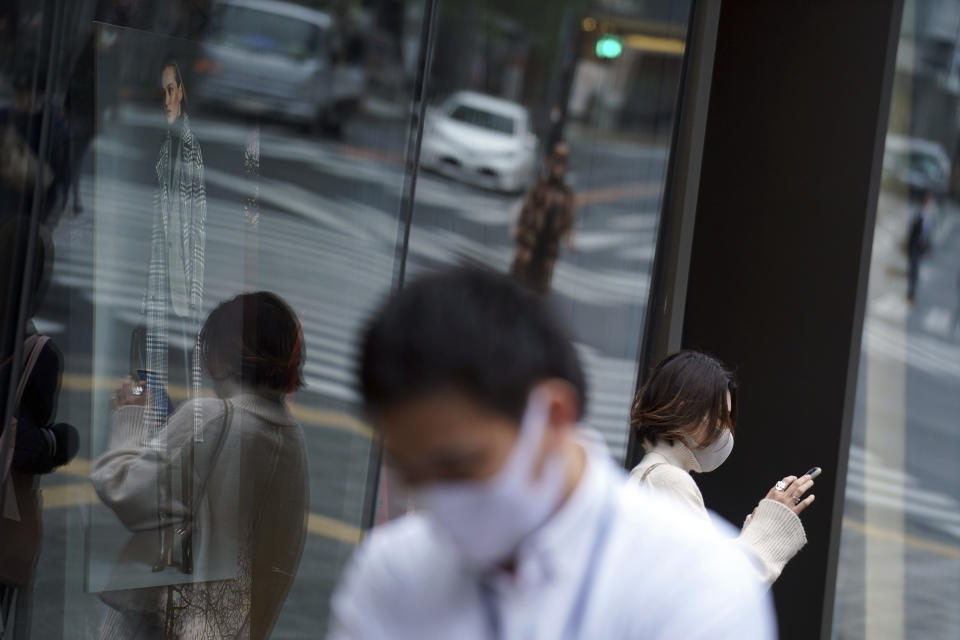 People wearing protective masks to help curb the spread of the coronavirus pause near a shopping building Wednesday, Nov. 25, 2020, in Tokyo. The Japanese capital confirmed more than 400 new coronavirus cases on Wednesday. (AP Photo/Eugene Hoshiko)