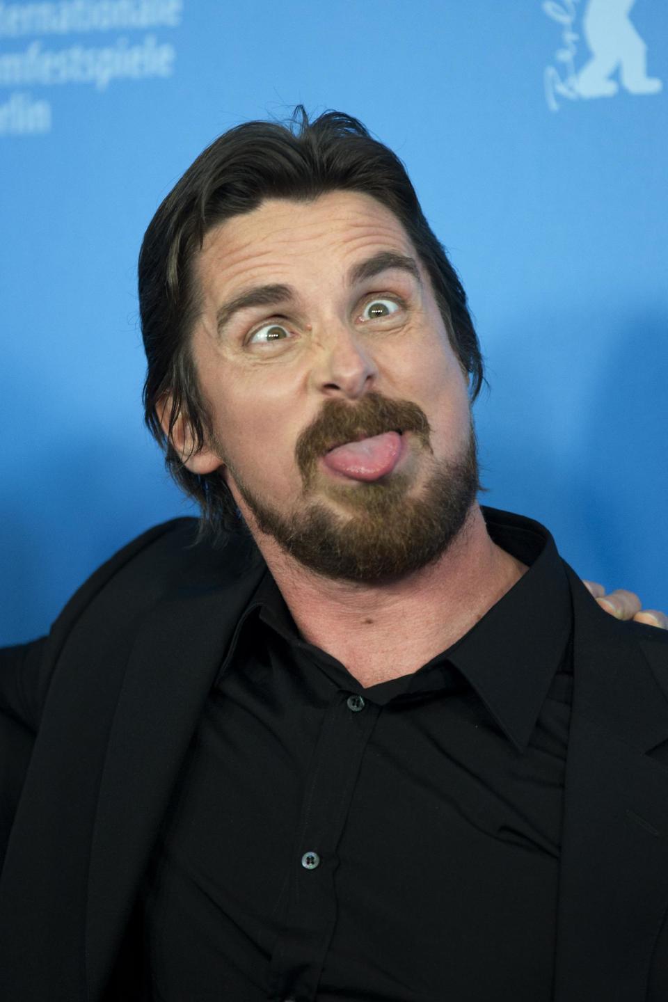 Actor Christian Bale pokes his tongue out at photographers during the photo call for the film American Hustle during the International Film Festival Berlinale, in Berlin, Friday, Feb. 7, 2014. (AP Photo/Axel Schmidt)