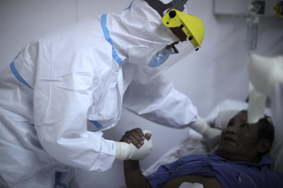 FILE - In this July 18, 2020 file photo, Dr. Matias Norte comforts a patient infected with COVID-19 at a hospital in Buenos Aires, Argentina. People are on edge in Argentina, where the number of new coronavirus cases is surging despite nearly five months of strict limits on movement and activities in Buenos Aires and the surrounding area. Argentina reached 1 million confirmed coronavirus cases on Monday, Oct. 19, 2020, according to the Ministry of Health. (AP Photo/Natacha Pisarenko, File)