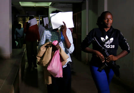 Gladys Kaari covers her face as she is escorted from the Mililani Law Courts where she appeared as a suspect in connection with the attack at the DusitD2 complex, in Nairobi, Kenya January 18, 2019. REUTERS/Thomas Mukoya