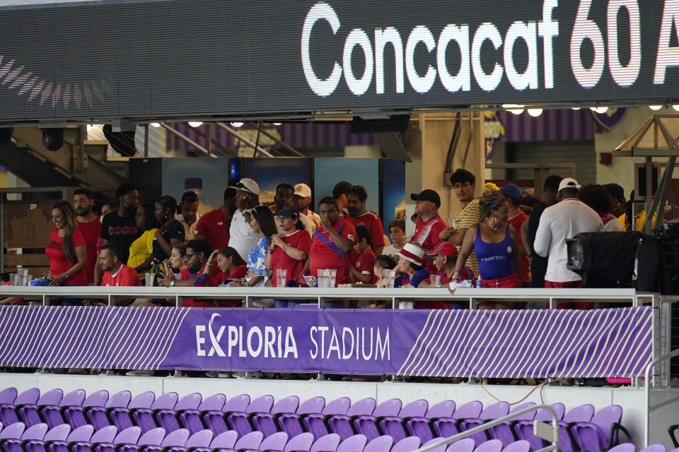 Un grupo de hinchas busca guarecerse durante una interrupción del partido entre Jamaica y Costa Rica en Orlando, Florida, el martes 20 de julio de 2021 (AP Foto/John Raoux)