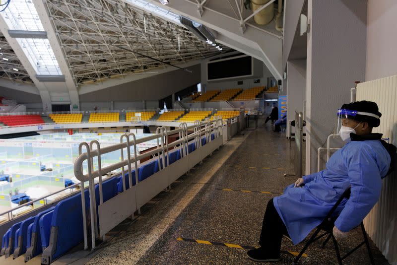 Un guardia de seguridad vigila en una clínica improvisada contra la fiebre que se instaló en un recinto deportivo mientras continúan los brotes de la enfermedad por coronavirus (COVID-19) en Pekín