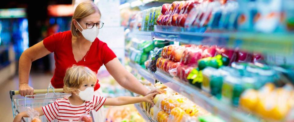 Mother and child wearing surgical face mask buying fruit in supermarket