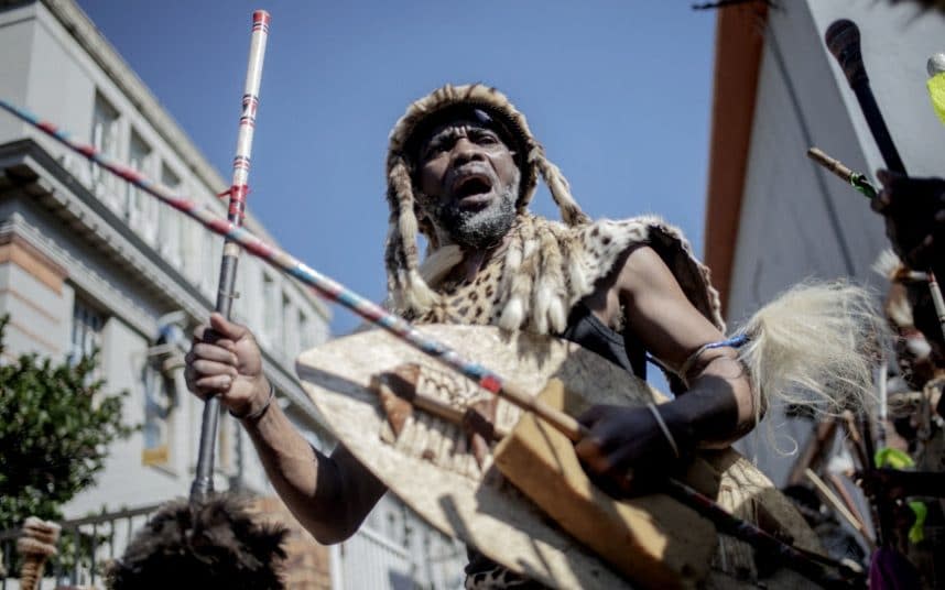 A traditionally dressed Zulu man dances during a gathering in front of a morgue in Johannesburg - LUCA SOLA /Getty
