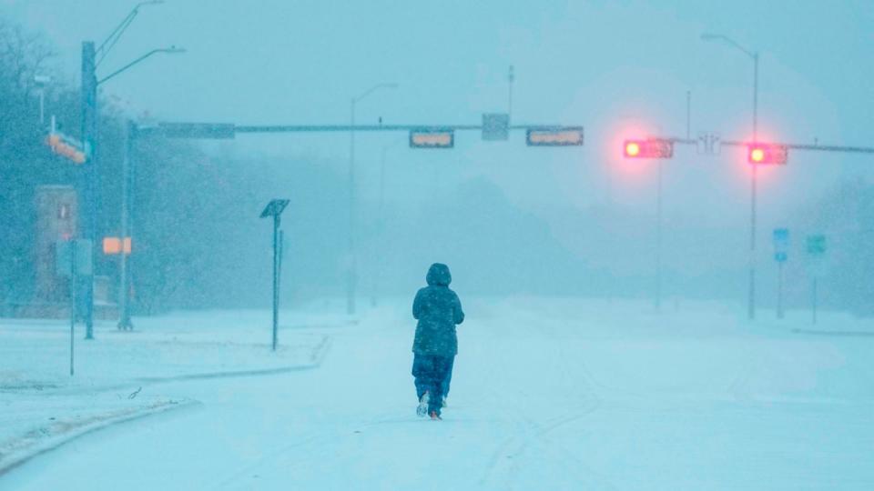 PHOTO: A jogger trots on a snow-covered road during a winter storm, Jan. 15, 2024, in Grand Prairie, Texas. (Julio Cortez/AP)