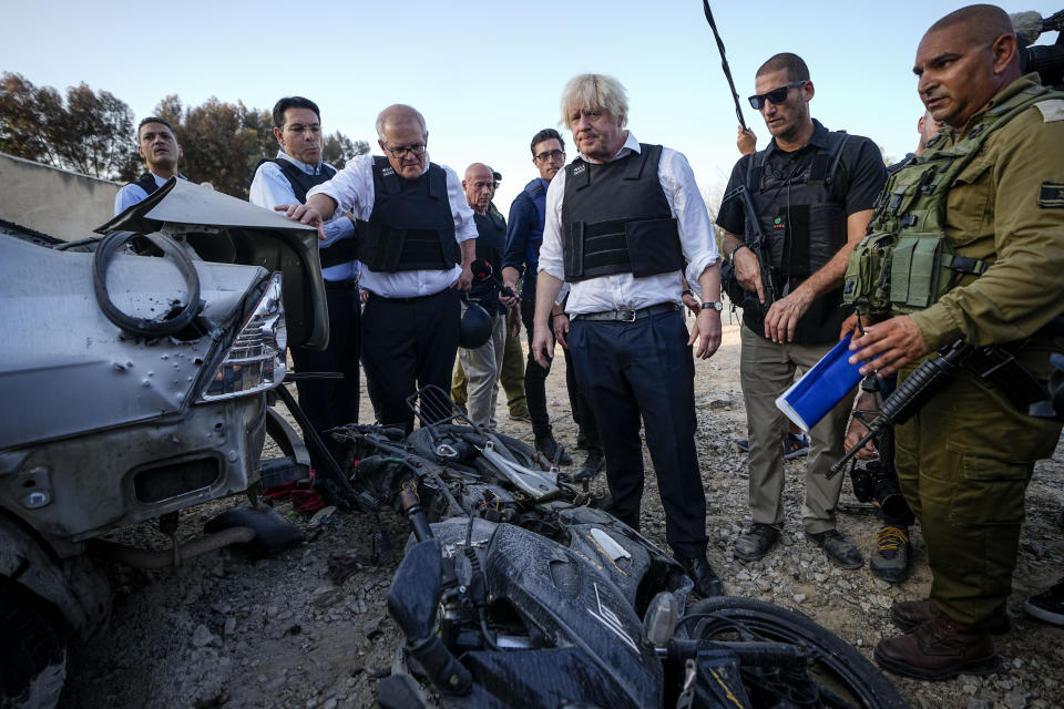 Former British Prime Minister Boris Johnson, center right, and former Australian Prime Minister Scott Morrison, center left, visit kibbutz Kfar Azza, Israel, Sunday, Nov. 5, 2023. Kibbutz Kfar Azza was one of the locations attacked by Hamas on Oct. 7. (AP Photo/Ariel Schalit)