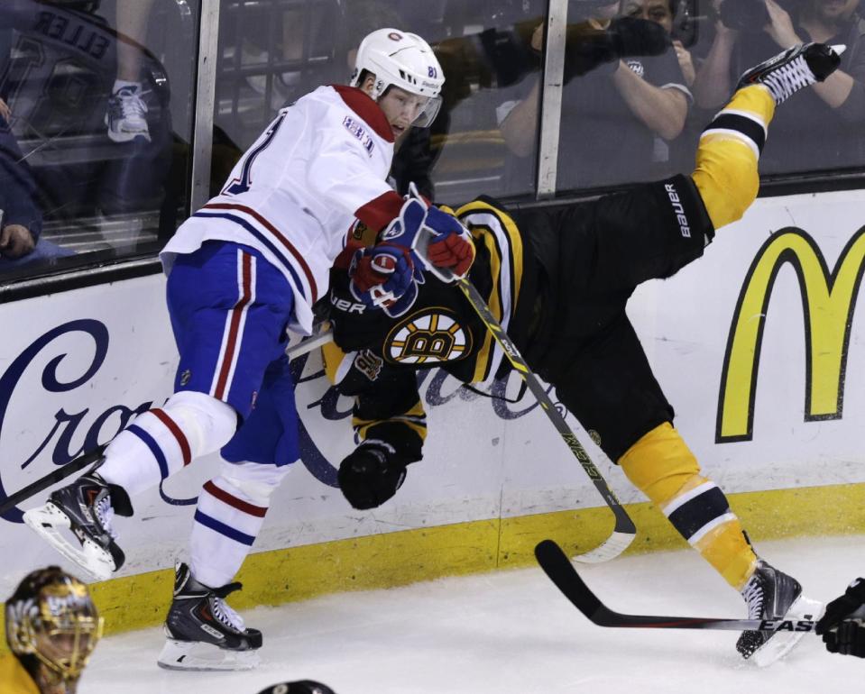 Boston Bruins defenseman Johnny Boychuk, right, is upended while chasing the puck against Montreal Canadiens center Lars Eller (81) during the first period of Game 5 in the second-round of the Stanley Cup hockey playoff series in Boston, Saturday, May 10, 2014. (AP Photo/Charles Krupa)