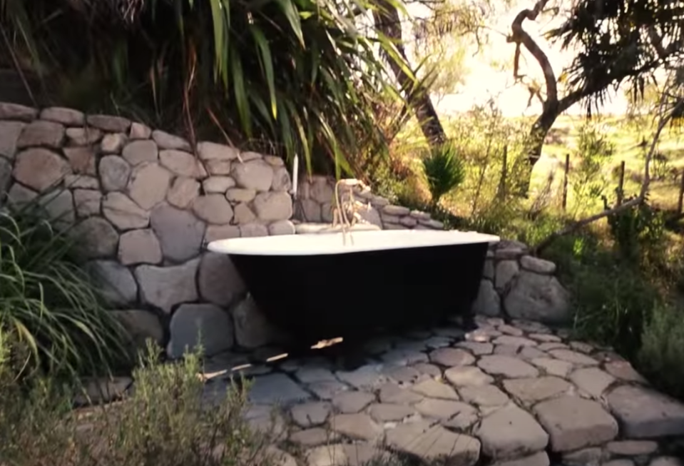 An iron bathtub sits among decorative rocks outside