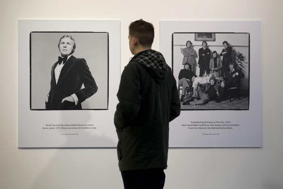 FILE - In this file photo dated Thursday Jan. 31, 2013, a man views photographs of footballers by Terry O'Neill are seen on display at the Strike A Pose: 50 Years of Football & Fashion, exhibition preview at the National Football Museum in Manchester, England. Terry O'Neill photos seen are World Cup England soccer team captain Bobby Moore at left taken in 1975, and a gathering of some England soccer player greats taken in 1972. Iconic photographer Terry O'Neill, who chronicled the swinging 60s generation, died Saturday Nov. 17, 2019, aged 81, according to an announcement from his licensing agency. (AP Photo/Jon Super, FILE)