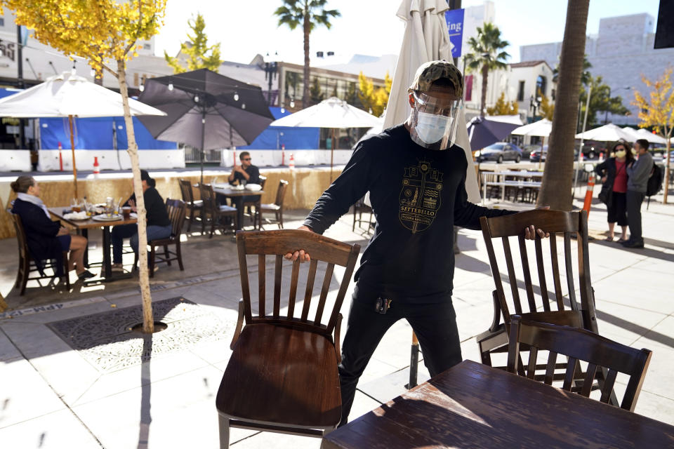 FILE - In this Dec. 1, 2020, file photo, General manager Damien Williams prepares outdoor seating at Settebello Pizzeria Napoletana in Pasadena, Calif. States faced a deadline on Friday, Dec. 4, 2020, to place orders for the coronavirus vaccine as many reported record infections, hospitalizations and deaths, while hospitals were pushed to the breaking point — with the worst feared yet to come. (AP Photo/Marcio Jose Sanchez, File)