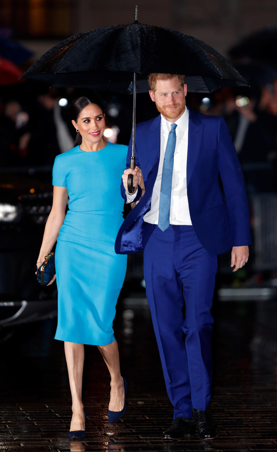 Prince Harry holds an umbrella over himself and Meghan Markle