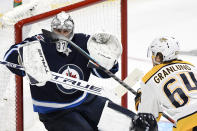 Winnipeg Jets goaltender Connor Hellebuyck (37) watches the puck as Nashville Predators' Mikael Granlund (64) reaches for it during the second period of NHL hockey game action in Winnipeg, Manitoba, Saturday, Oct. 23, 2021. (Fred Greenslade/The Canadian Press via AP)