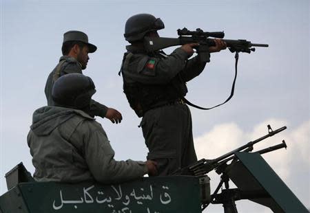 Afghan policemen take their positions atop a military vehicle near an election commission office during an attack by gunmen in Kabul March 29, 2014. REUTERS/Mohammad Ismail