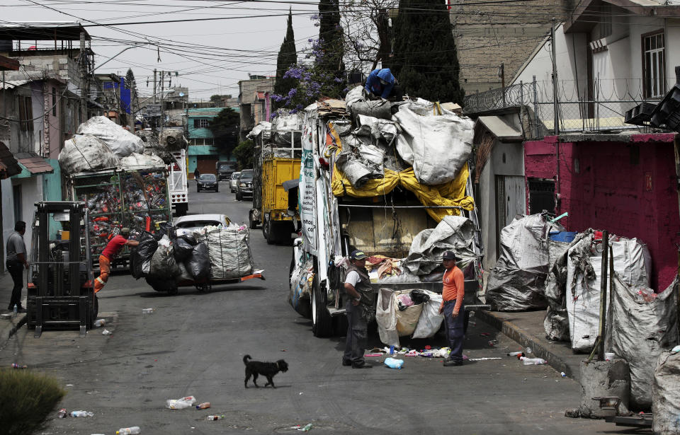 Trash pickers unload garbage in Mexico City, Monday, March 29, 2021. In Mexico, scavengers help municipal workers on garbage trucks and often collect trash from neighborhoods not served by authorities. (AP Photo/Marco Ugarte)