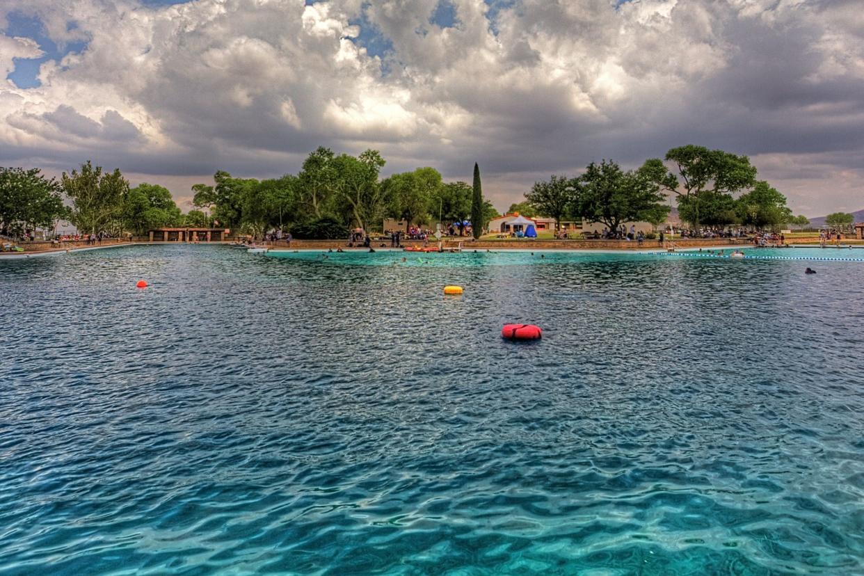 Balmorhea State Park, Toyahvale, Texas, pool in the foreground with trees and shoreline in the background, clouds and blue sky