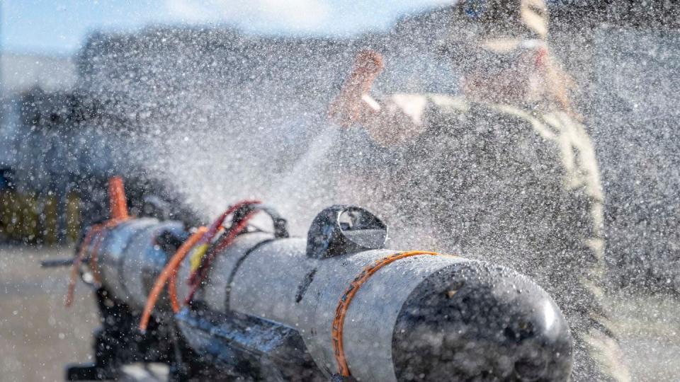 Fire Controlman 1st Class Jordan Sigler, assigned to Unmanned Undersea Vehicle Flotilla 1, conducts a fresh water wash down of an Iver small UUV in Keyport, Washington, on Feb. 22, 2024. (MC1 Scott Barnes/US Navy)