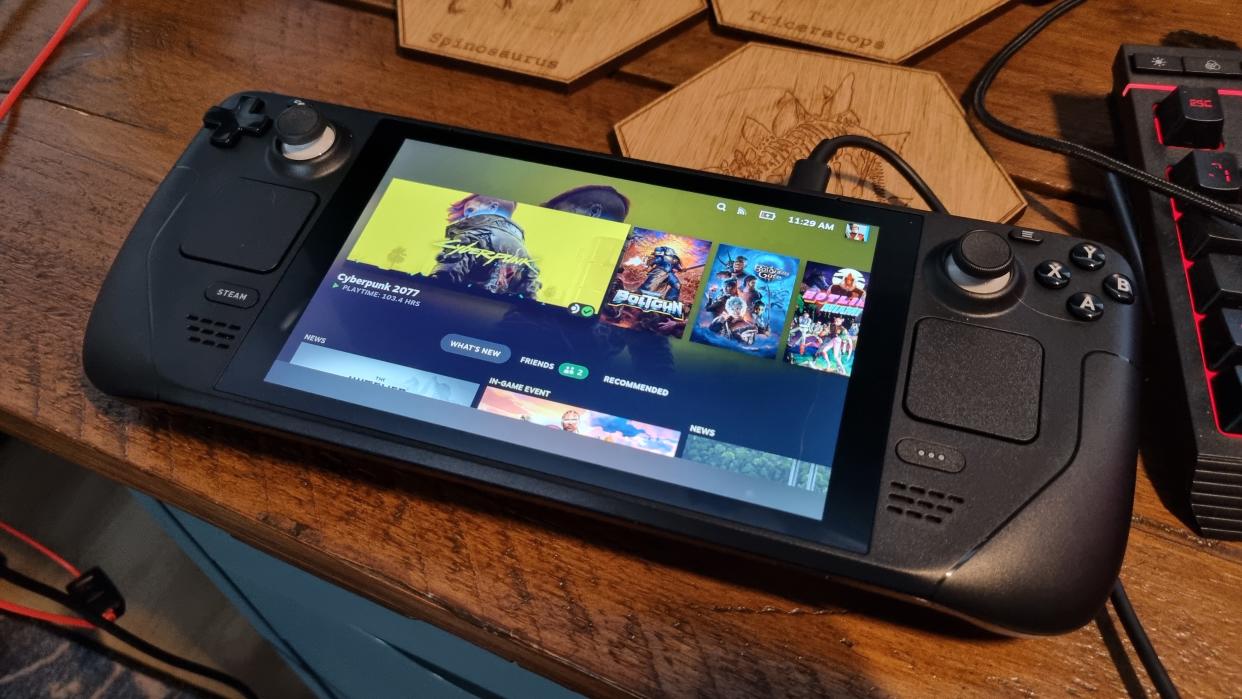  A Steam Deck LCD on a wooden desk, with the SteamOS menu screen on the display. 