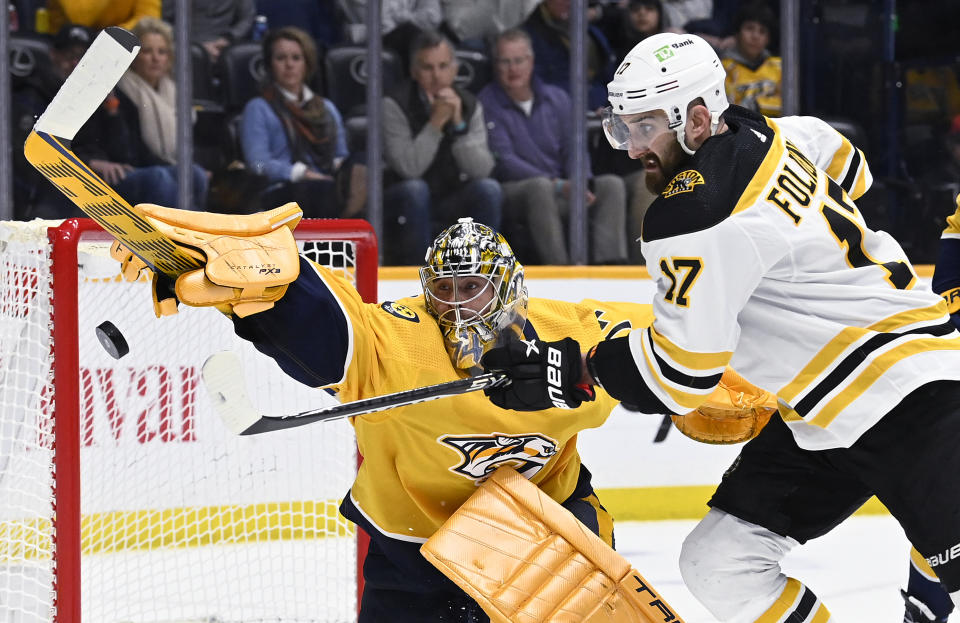 Nashville Predators goaltender Juuse Saros and Boston Bruins left wing Nick Foligno (17) reach for the puck during the first period of an NHL hockey game Thursday, Feb. 16, 2023, in Nashville, Tenn. (AP Photo/Mark Zaleski)