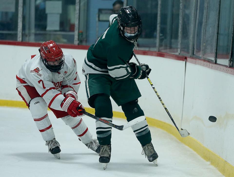 Marshfield’s Nicholas Souretis looks to bounce the puck off the boards while Hingham’s Chase McKenna gives chase during third period action of their game at Pilgrim Arena on Wednesday, Jan. 20, 2021.