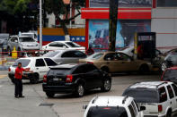 A gas station worker tries to organize the lines as people wait to fill the tanks of their cars at a gas station of the state oil company PDVSA in Caracas, Venezuela March 23, 2017. REUTERS/Carlos Garcia Rawlins