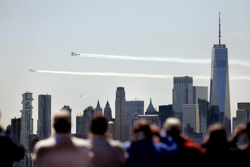 People watch as a formation of the Blue Angels and Thunderbirds flight teams pass in front of the New York City skyline as seen from in Weehawken, N.J., Tuesday, April 28, 2020. The flyover was in salute to first responders in the fight against the new coronavirus. (AP Photo/Seth Wenig)