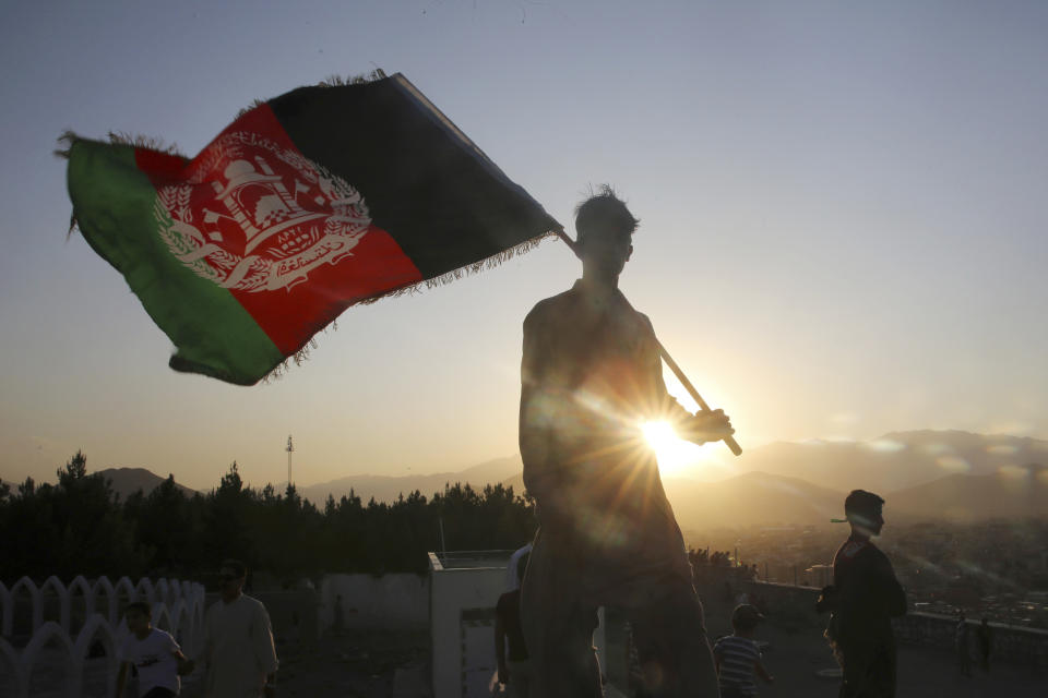 FILE - In this Aug. 19, 2019, file photo, a man waves the Afghan national flag during Independence Day celebrations in Kabul, Afghanistan. The U.N. mission in Afghanistan report released on Monday, July 27, 2020, has noted a drop in the number of civilians killed in violence in the first six months of this year, compared to the same period last year. (AP Photo/Rafiq Maqbool, File)