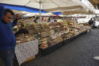 A seller waits for customers at the Campo de' Fiori street market, in Rome, Saturday, March 7, 2020. With the coronavirus emergency deepening in Europe, Italy, a focal point in the contagion, risks falling back into recession as foreign tourists are spooked from visiting its cultural treasures and the global market shrinks for prized artisanal products, from fashion to design. (AP Photo/Andrew Medichini)