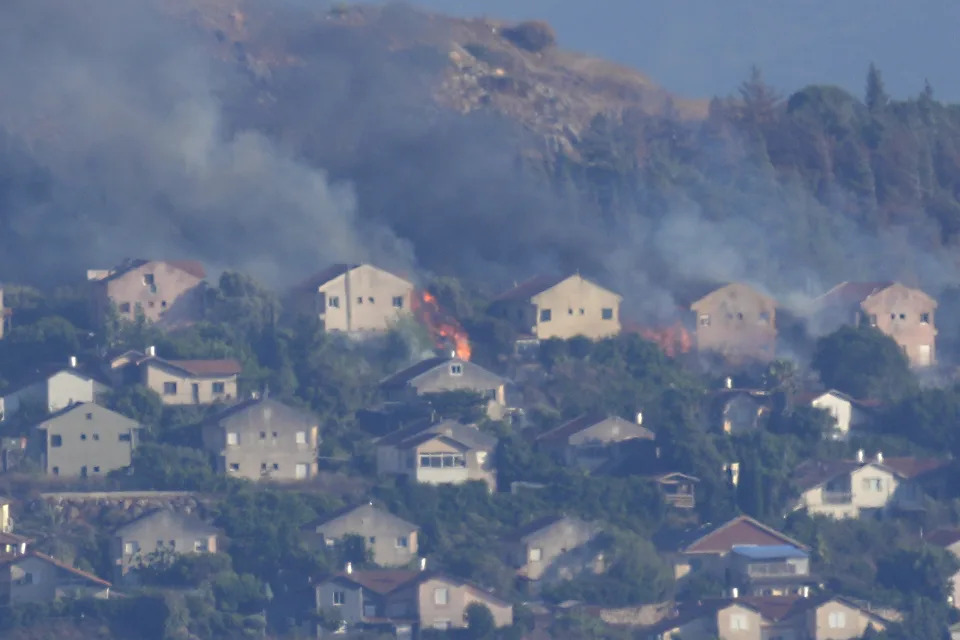 FILE - Fires and smoke rise at houses in the northern Israeli border town of Metula, hit by Hezbollah shelling, as seen from the Lebanese town of Marjayoun, Lebanon, June 22, 2024. U.S., European and Arab mediators are pressing to keep stepped-up cross-border attacks between Israel and Lebanon’s Hezbollah militants from spiraling into a nightmare Middle East-wide war that the world has feared for months. (AP Photo/Hussein Malla, File)