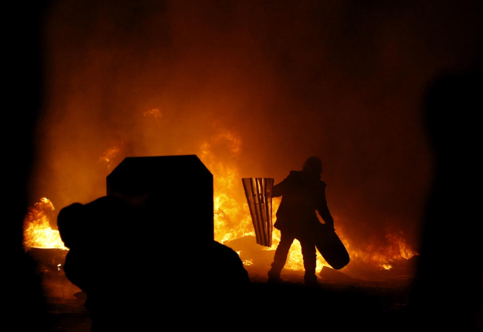 A protester throws a tire onto a fire during clashes with police in central Kiev, Ukraine, Friday Jan. 24, 2014. As riots spread from Ukraine's embattled capital to nearly half of the country, President Viktor Yanukovych promised Friday to reshuffle his government and make other concessions — but a top opposition leader said nothing short of his resignation would do. Hours after the president's comments, huge fireballs lit up the night sky in central Kiev and plumes of thick black smoke rose from burning tires at giant barricades erected by protesters. (AP Photo/Darko Vojinovic)