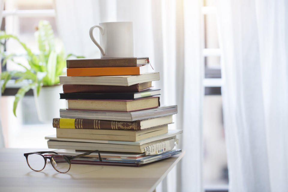 A stack of books on a table with a coffee mug on top