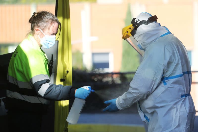 FILE PHOTO: An ambulance worker wearing a full personal protective equipment (PPE) is disinfected by a collage in Leganes