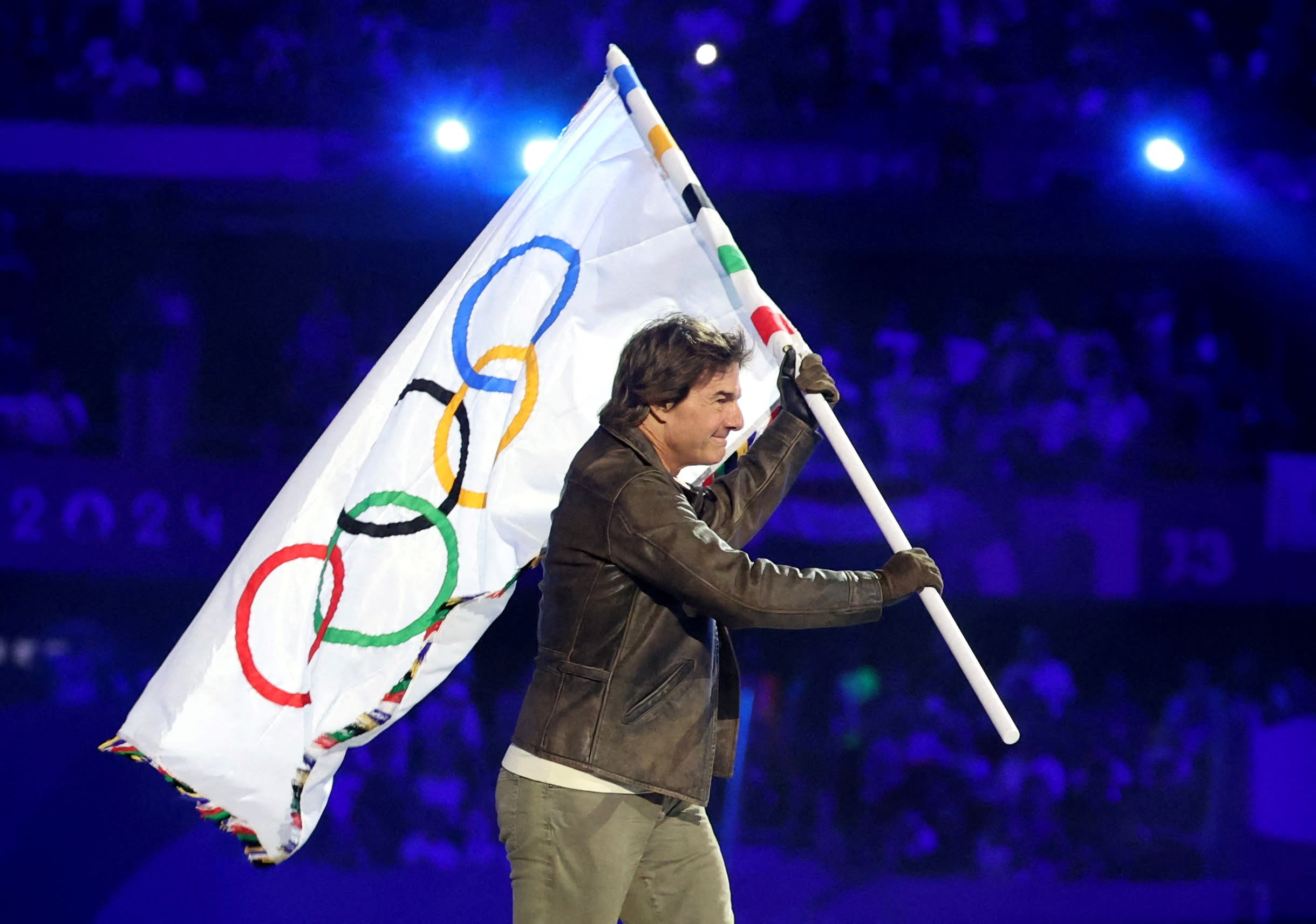 Tom Cruise holds the Olympic flag.