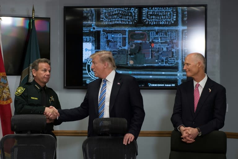 US President Donald Trump (C) shakes hands with Broward County Sheriff Scott Israel (L) as Florida Governor Rick Scott (R) looks on during Trump's visit to the sheriff's office