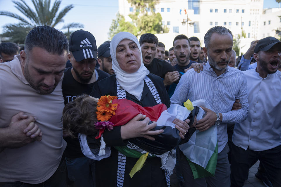 Ramallah governor Laila Ghannam, with a white scarf, carries the body of 2 1/2 year old Palestinian toddler Mohammed al-Tamimi upon his arrival at the Palestine Medical Complex, in the West Bank city of Ramallah, Monday, June 5, 2023. The Palestinian toddler who was shot by Israeli troops in the occupied West Bank last week died of his wounds on Monday, Israeli hospital officials said. (AP Photo/Nasser Nasser)