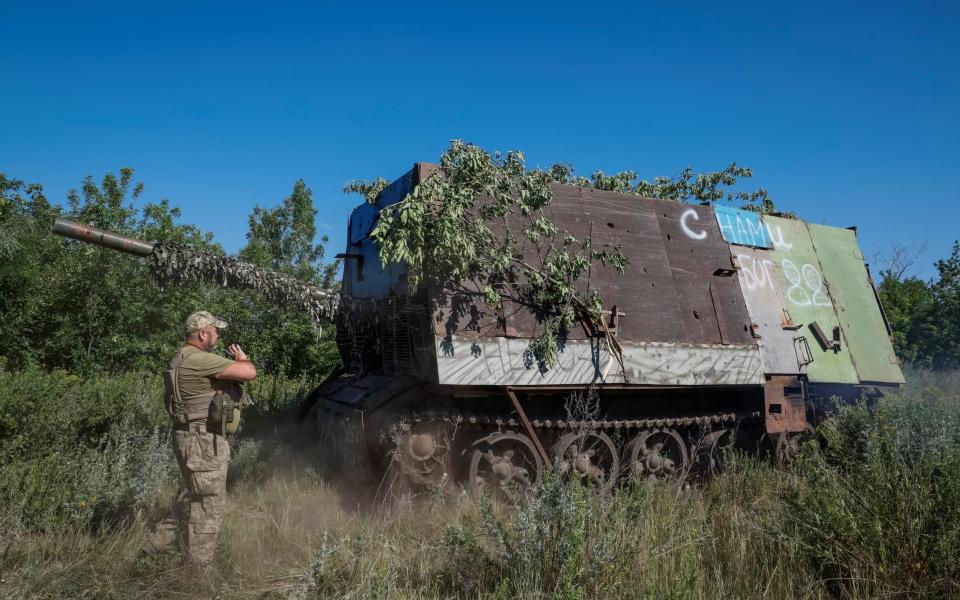 A Ukrainian serviceman of the 22nd Separate Mechanised Brigade stands next to a Russian T-62 Soviet main battle tank crafted with anti-drone protection