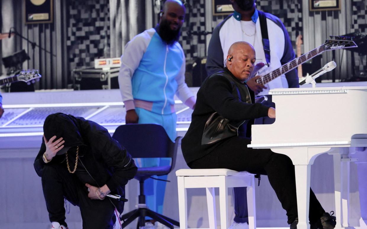 American Football - NFL - Super Bowl LVI Halftime Show - Cincinnati Bengals v Los Angeles Rams - SoFi Stadium, Inglewood, California, United States - February 13, 2022 Eminem takes a knee during the halftime show as Dr. Dre looks on REUTERS/Mike Segar TPX IMAGES OF THE DAY - Mike Segar/Reuters