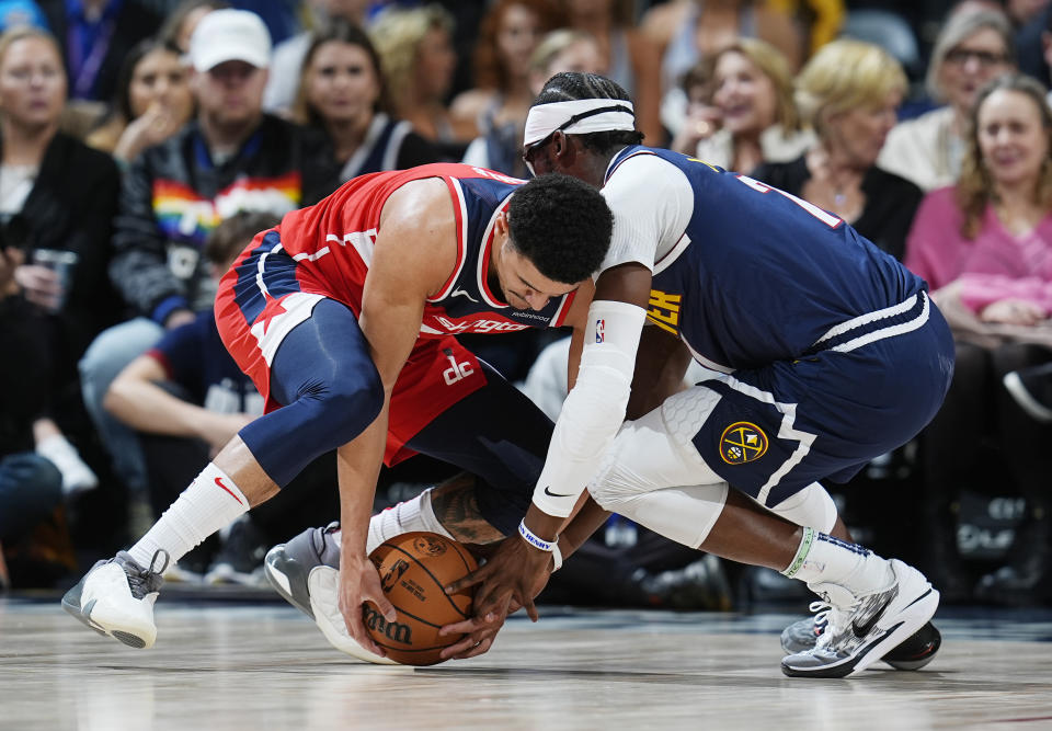 Washington Wizards guard Johnny Davis, left, fights for control of a loose ball with Denver Nuggets guard Reggie Jackson in the first half of an NBA basketball game Thursday, Feb. 22, 2024, in Denver. (AP Photo/David Zalubowski)
